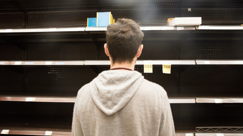 Homme devant des rayons vides en magasin – illustration du taux de rupture en retail.